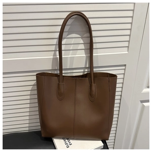 Detailed close-up of dark brown leather tote bag with vertical stitching and smooth texture