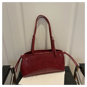 Close-up of vintage burgundy faux leather tote bag with stylish side drawstring detail