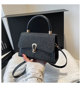 Détail du sac bandoulière noir pailleté avec boucle fer à cheval dorée et bandoulière