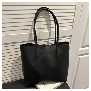 Close-up of black leather tote bag featuring sleek vertical stitching and slender straps