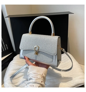 Détail du sac argenté avec rabat pailleté scintillant et fermoir métallique chic