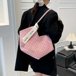 Pink tweed geometric tote bag with branded canvas strap shown on model in modern interior