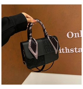 Detail of black patchwork shoulder bag with sequined fabric and houndstooth scarf handle