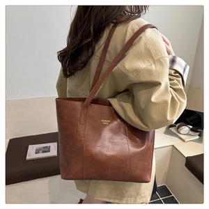 Vue détaillée du sac cabas en cuir marron caramel avec logo doré sur un mannequin femme