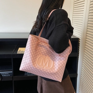 Pink tote bag with letter M print and shoulder strap shown in a modern interior setting