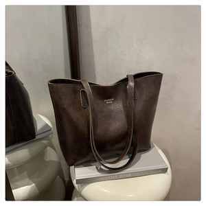 Détail d'un grand sac cabas marron foncé avec lettrage de mode sur un tabouret artistique