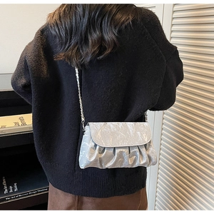 Detail of silver pleated crossbody bag with chain strap and metallic texture finish