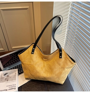 Detail of quilted suede texture and golden metal twist lock on yellow tote bag