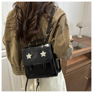 Détail d'un mini sac à dos noir en cuir avec étoiles argentées porté par un mannequin