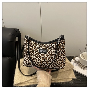 Dettaglio della borsa tote leopardata con manico in pelle nera e tracolla regolabile