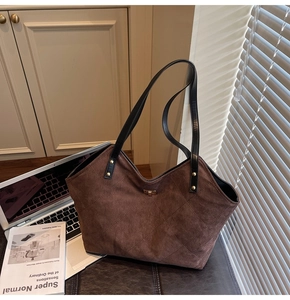 Detail of dark brown quilted tote bag with matte finish and black leather straps