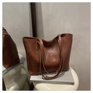 Gros plan du sac cabas en cuir marron avec texture vintage sur un tabouret blanc