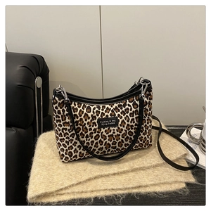 Macro shot of leopard print hobo bag texture and black leather piping with silver buckle