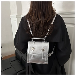 Mini sac à dos argenté avec détails d'étoiles 3D porté sur un manteau noir d'hiver