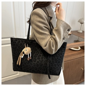 Détail du sac cabas léopard avec breloque en peluche sur mannequin en costume brun