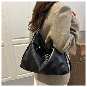 Classic black oversized tote bag with metal buckle and tie detail shown on a shoulder