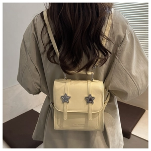 Détail du mini sac à dos jaune clair avec boucles d'étoiles argentées et texture cuir