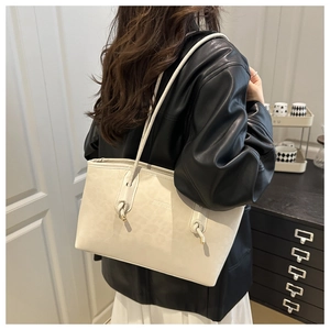 Dettaglio della borsa tote crema leopardata con spalline annodate e punte in metallo