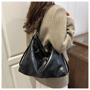 Detail of adjustable strap with gold hardware on a black leather tote bag for women