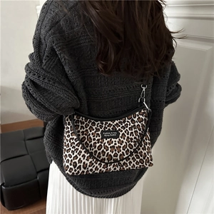 Retro leopard print shoulder bag with black strap worn by a model in a minimalist setting