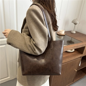 Grand sac cabas rétro marron foncé au fini brillant porté par un mannequin à l'épaule