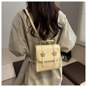 Détail d'un sac à dos en cuir jaune crème avec étoiles argentées porté par un mannequin