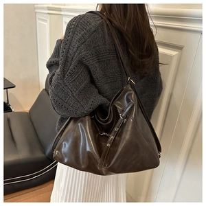 Detail of a large vintage brown tote bag showing side buckle and glossy leather texture