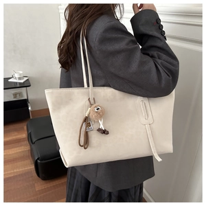 Détail d'un sac cabas beige en daim avec un charmant pompon décoratif en fourrure