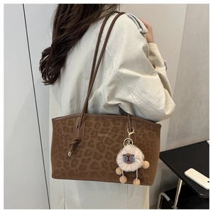 Dettaglio borsa tote leopardata marrone con ciondolo a forma di pecora e manici in pelle