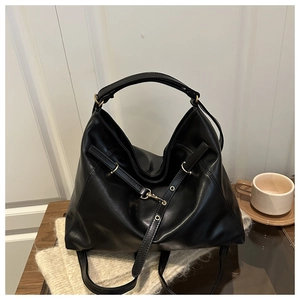 Detail of a large black hobo shoulder bag with metal ring and decorative strap