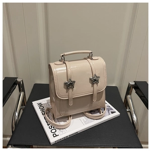 Détail du mini sac à dos beige brillant avec boucles d'étoiles sur une chaise en cuir