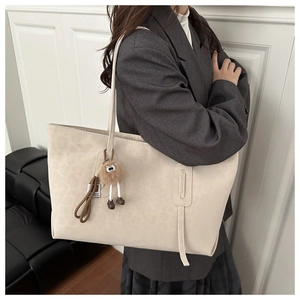 Détail d'un sac cabas beige à imprimé léopard avec un charmant pendentif ours en peluche