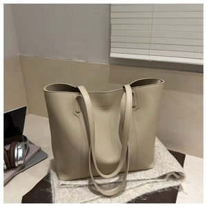 Detail of beige faux leather tote bag with gold lettering on soft grey knit blanket