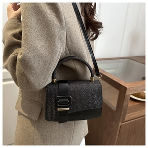 Detail of a chic black glitter crossbody bag with square buckle worn by a model