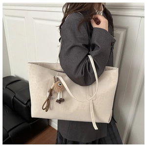 Détail d'un grand sac cabas léopard beige en daim avec un pendentif en peluche ours