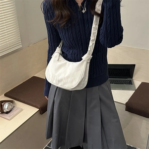 White crescent crossbody bag with ruffled drawstring strap on a casual model outfit