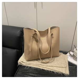 Detail of beige faux leather tote bag with gold lettering on a soft scarf background
