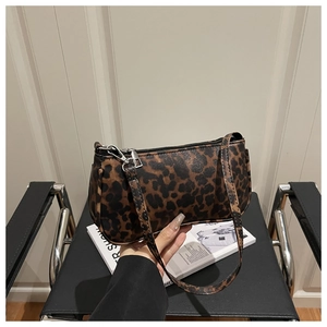 Detail showing woman holding a trendy leopard print underarm bag with silver zipper