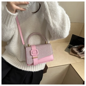 Detail of pink mini square bag with glitter flap and gold hardware on model