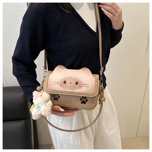 Detail of cartoon cat crossbody bag featuring plush bear charm and pink paw prints