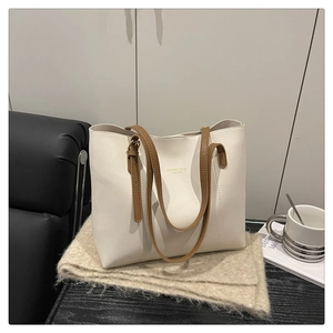 Detail of white tote bag featuring gold embossed lettering and brown leather straps