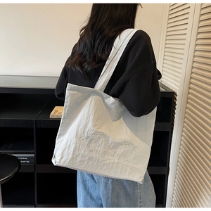 Detail of light blue canvas tote bag featuring heart embroidery and wide shoulder straps