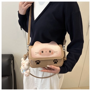 Detail of cute cat-shaped crossbody bag with pink kitten face flap and plush bear charm