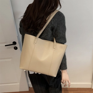 Minimalist beige leather tote bag for women shown as a stylish shoulder bag on model