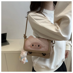 Detail of pink cat-shaped crossbody bag with paw print and cute bear plush charm
