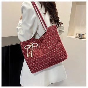 Detail der roten Tweed-Tasche mit Goldfäden und Perlen-Schleife auf weißem Blazer