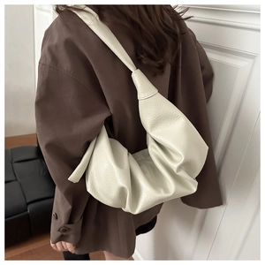 Détail du sac croissant plissé blanc cassé avec texture grainée et bandoulière nouée