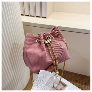 Détail d'un sac seau en velours rose avec cordon et chaîne dorée à pendentif perle