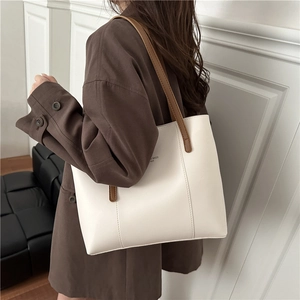 Minimalist beige leather tote bag with brown straps shown on shoulder for 2025 autumn style