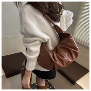 Détail d'un grand sac hobo marron foncé avec plis naturels et texture cuir souple